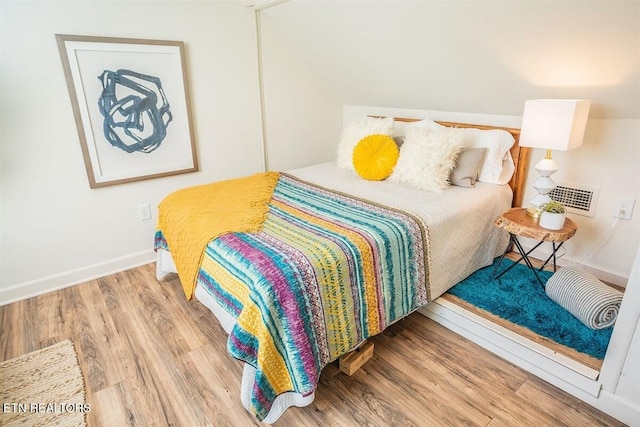 bedroom featuring baseboards, visible vents, and wood finished floors
