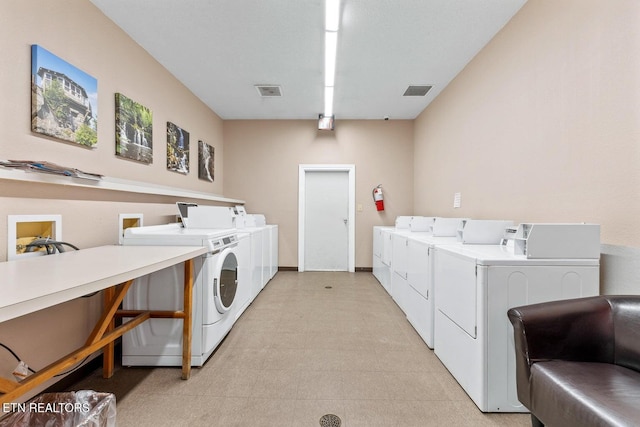 community laundry room featuring light floors, independent washer and dryer, and visible vents
