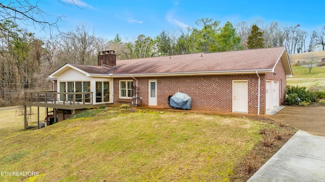 back of house with a wooden deck, a garage, and a lawn