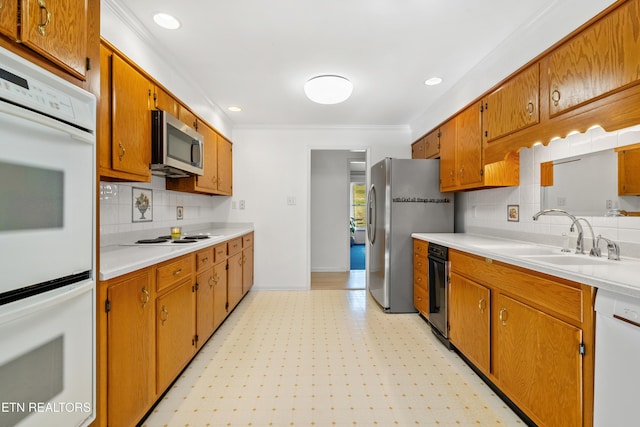 kitchen with crown molding, stainless steel appliances, tasteful backsplash, and sink