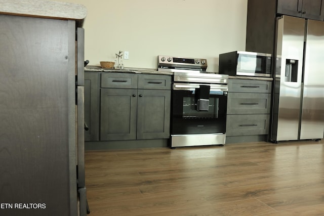 kitchen with stainless steel appliances, gray cabinets, and hardwood / wood-style floors