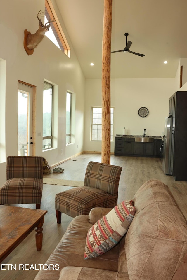 living room featuring sink, high vaulted ceiling, ceiling fan, and light wood-type flooring