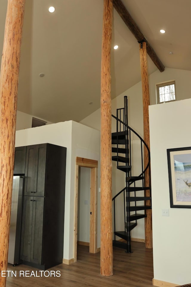 stairway with beamed ceiling, hardwood / wood-style floors, and high vaulted ceiling