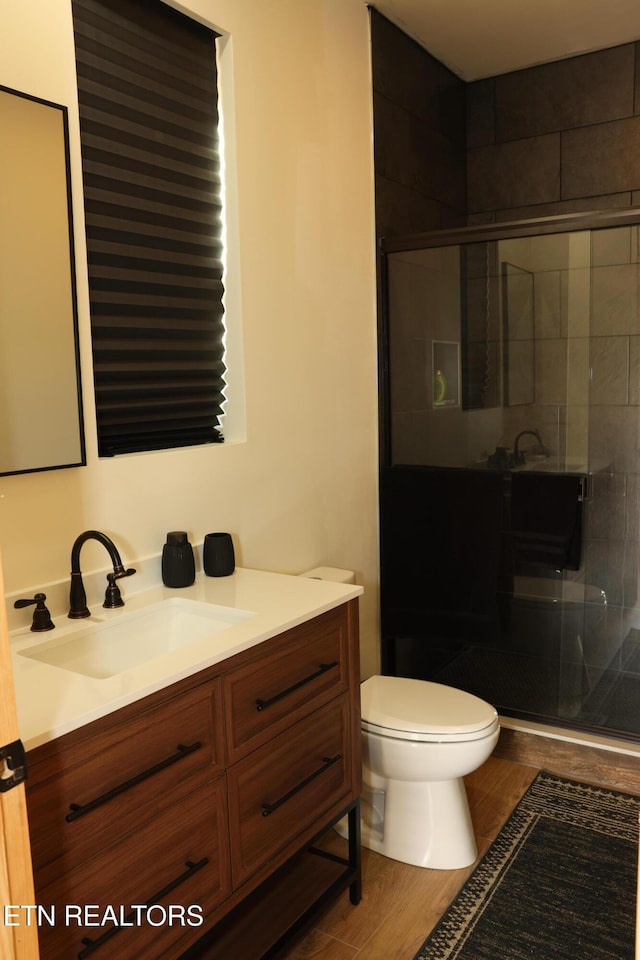 bathroom featuring vanity, wood-type flooring, toilet, and a shower with shower door