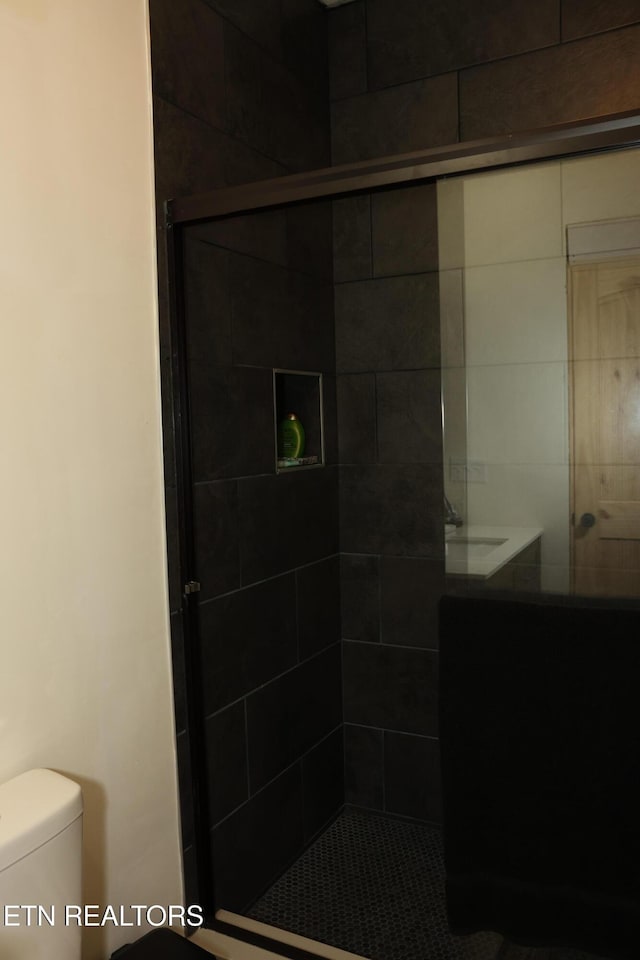 bathroom with toilet and a shower with shower door