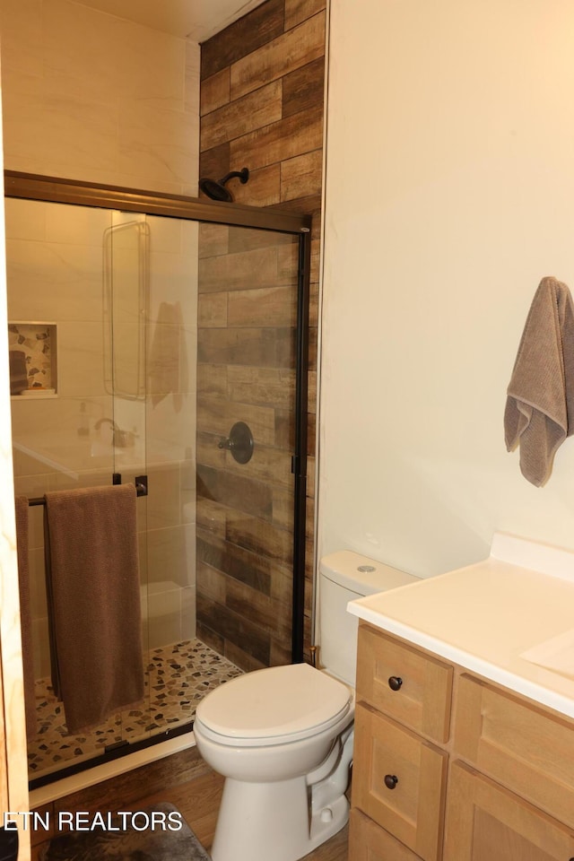 bathroom featuring walk in shower, vanity, toilet, and hardwood / wood-style floors