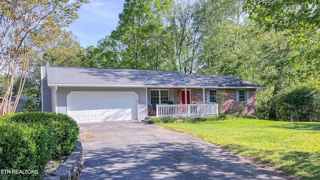 ranch-style home with a garage, a front yard, and covered porch