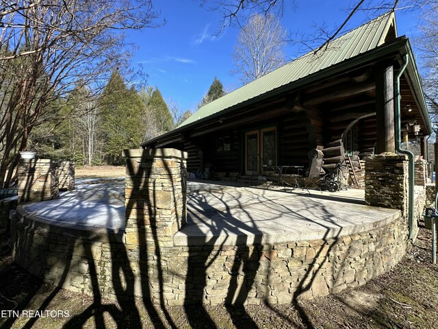 view of side of property with metal roof, french doors, a patio area, and log siding