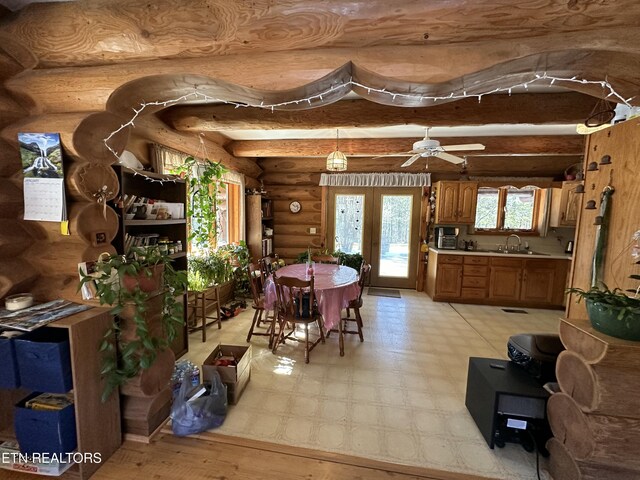 dining area featuring log walls, beam ceiling, and a ceiling fan