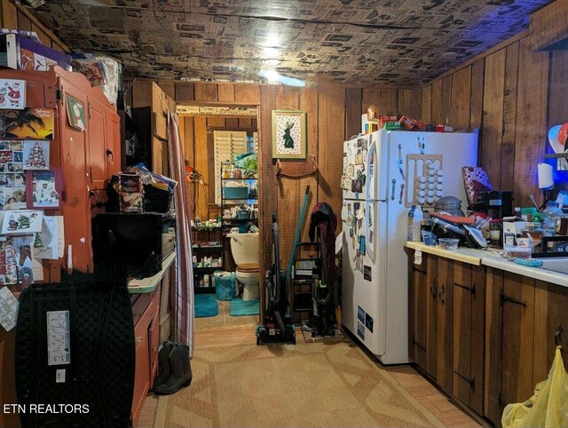 kitchen with wood walls, light countertops, and freestanding refrigerator