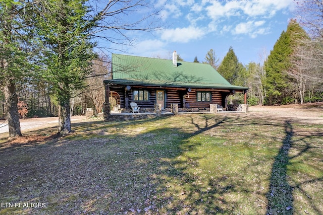 log home with a chimney, a porch, a front yard, metal roof, and log siding