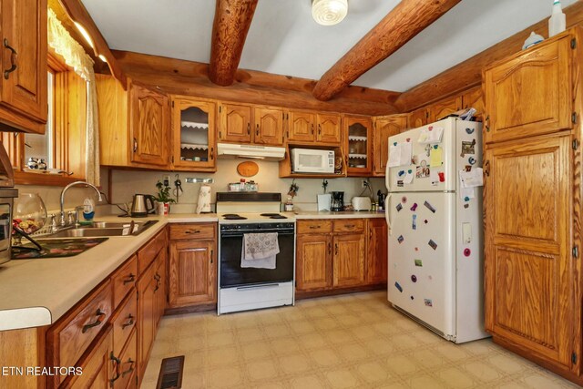 kitchen with white appliances, under cabinet range hood, brown cabinets, and a sink