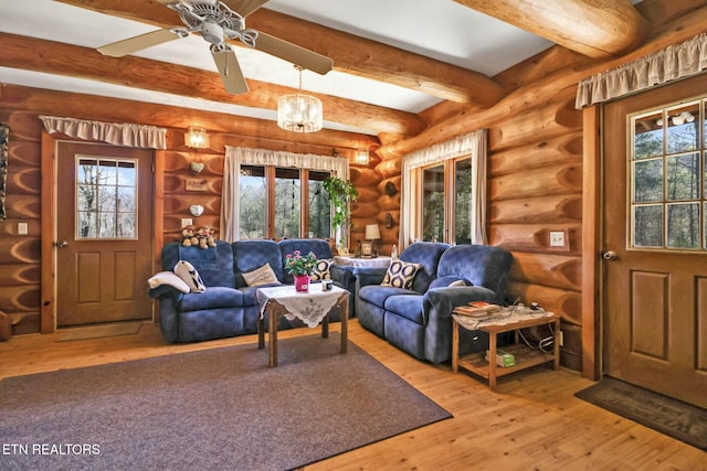 living area with rustic walls, a healthy amount of sunlight, beamed ceiling, and hardwood / wood-style flooring