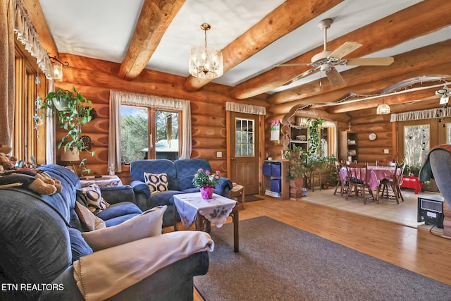 living area featuring ceiling fan with notable chandelier, wood finished floors, and beam ceiling