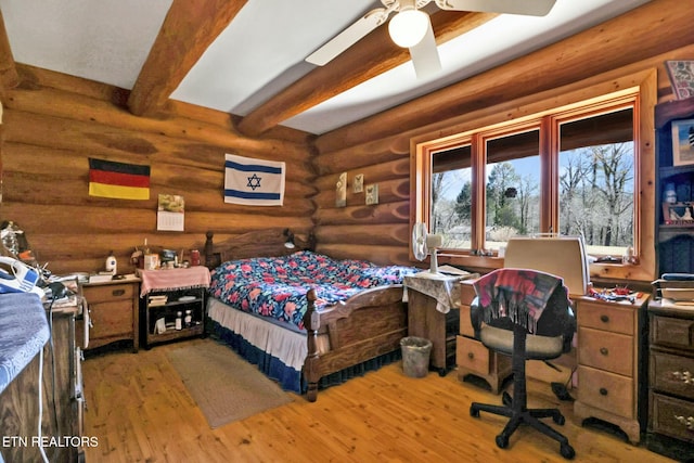 bedroom with beamed ceiling, rustic walls, and hardwood / wood-style flooring