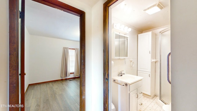 bathroom with vanity, hardwood / wood-style floors, and a shower with door