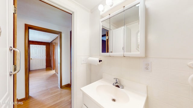 bathroom with wood-type flooring, tile walls, and vanity