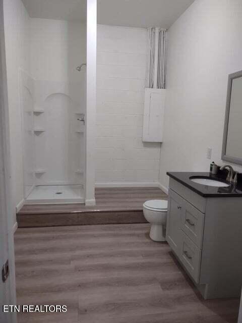 full bathroom featuring hardwood / wood-style flooring, washtub / shower combination, vanity, and toilet