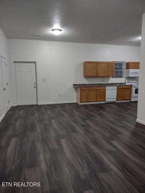 kitchen featuring white appliances, dark hardwood / wood-style floors, and a textured ceiling