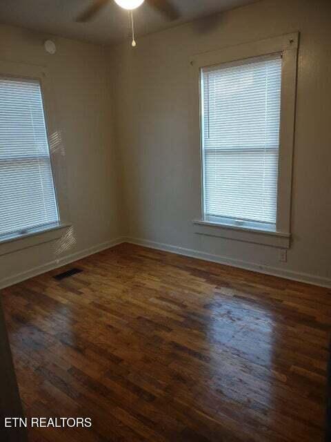 empty room with dark hardwood / wood-style flooring and ceiling fan