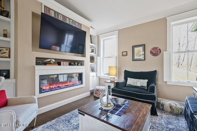 living room with dark wood-style floors, a glass covered fireplace, crown molding, and baseboards