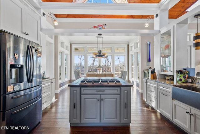 kitchen featuring stainless steel appliances, dark countertops, hanging light fixtures, and a kitchen island