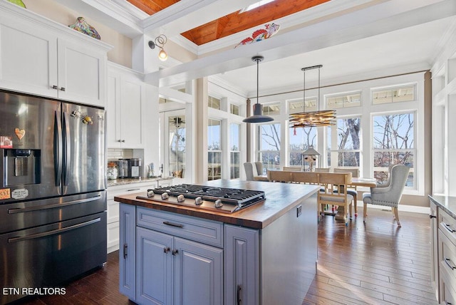 kitchen with stainless steel appliances, wood counters, white cabinetry, a center island, and crown molding