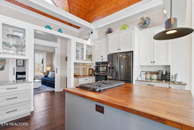 kitchen with stainless steel appliances, butcher block counters, white cabinetry, ornamental molding, and glass insert cabinets