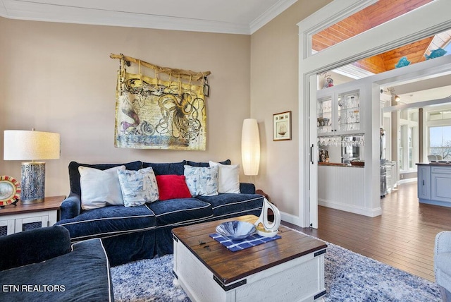 living room with crown molding, baseboards, and wood finished floors