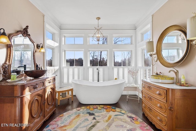 bathroom featuring a soaking tub, ornamental molding, wood finished floors, and vanity