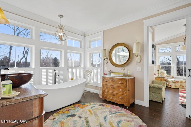 ensuite bathroom featuring a wealth of natural light, a freestanding bath, crown molding, and wood finished floors