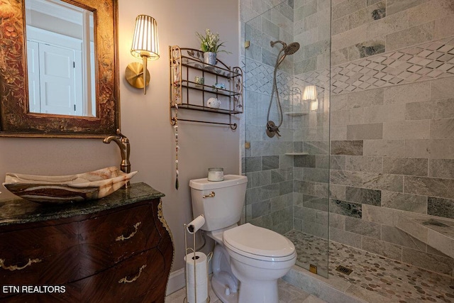 bathroom with tiled shower, vanity, and toilet