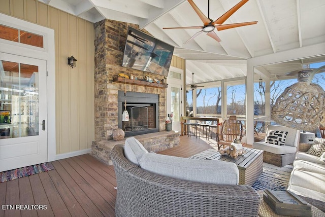 sunroom featuring vaulted ceiling with beams, ceiling fan, and a stone fireplace