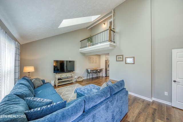 living room featuring dark hardwood / wood-style flooring, a skylight, high vaulted ceiling, and a textured ceiling