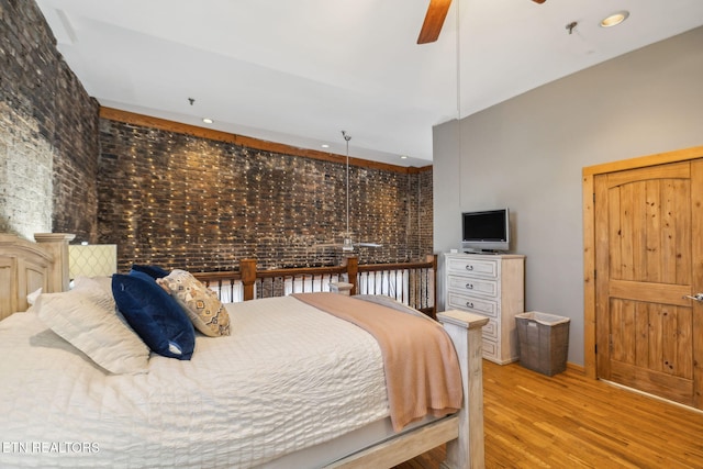 bedroom featuring brick wall and light hardwood / wood-style flooring