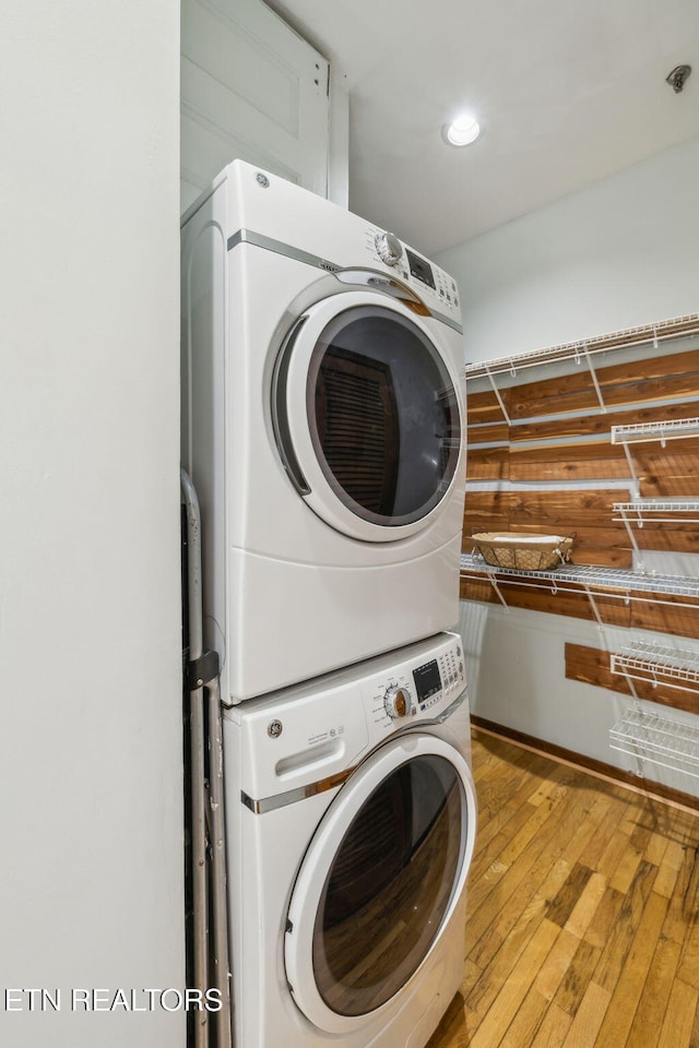 laundry room with stacked washer / drying machine and light wood-type flooring