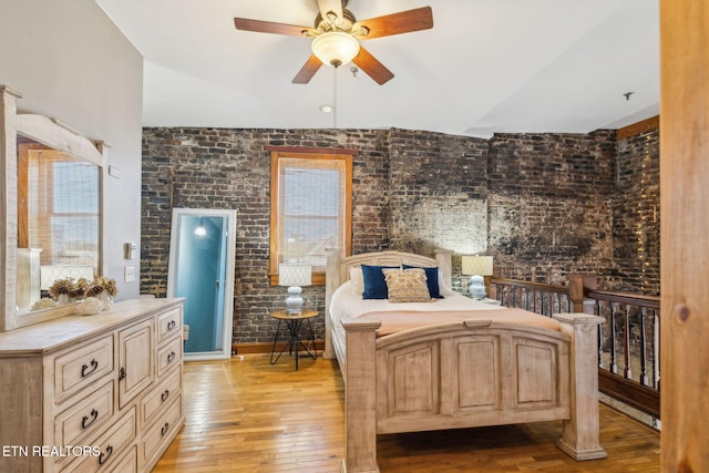 bedroom with light hardwood / wood-style floors, ceiling fan, and brick wall