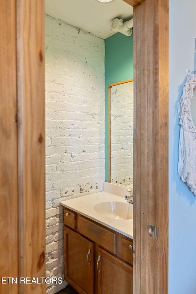 bathroom featuring brick wall and vanity