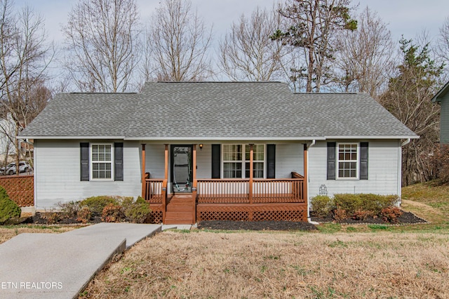 view of front of home with roof with shingles, a porch, and a front lawn