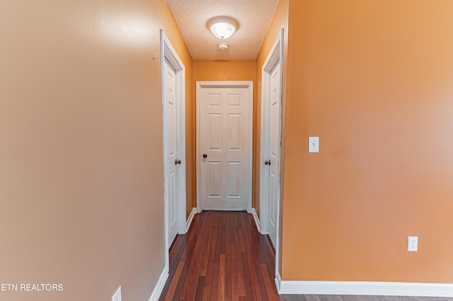 hallway with dark wood-type flooring and a textured ceiling