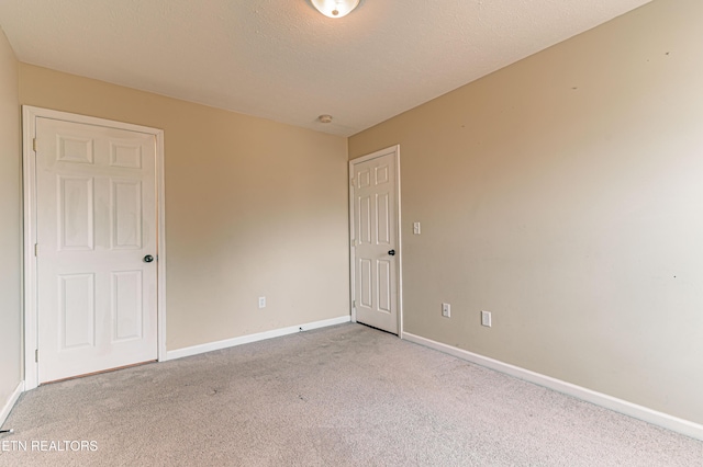 empty room with light carpet and a textured ceiling