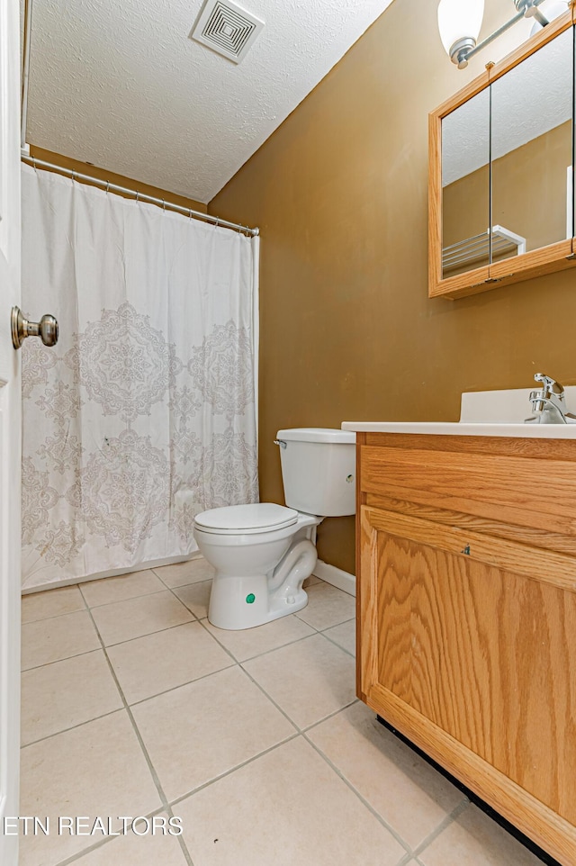 bathroom featuring vanity, toilet, tile patterned flooring, and a textured ceiling