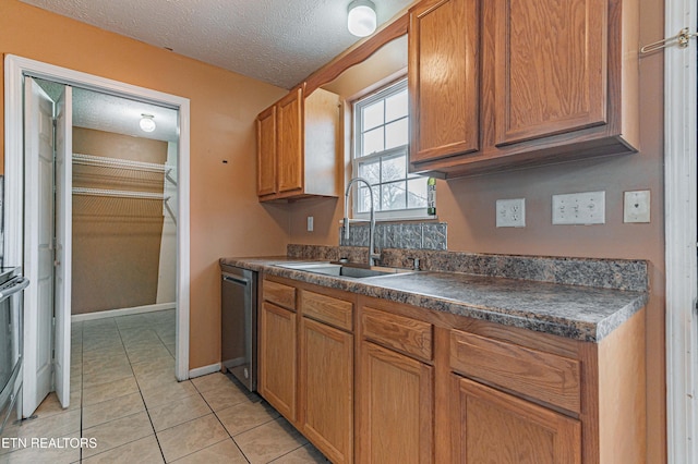 kitchen with stainless steel appliances, sink, light tile patterned floors, and a textured ceiling