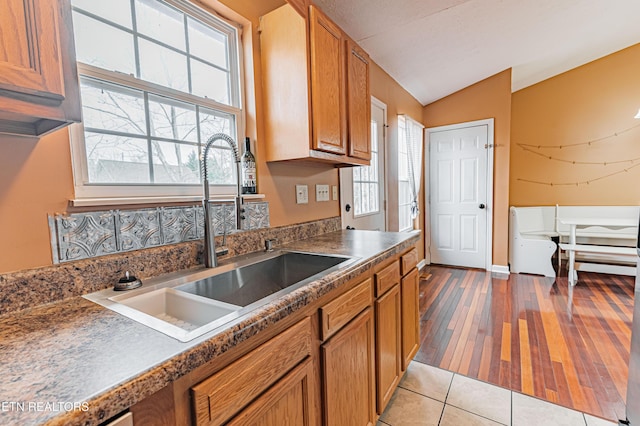 kitchen featuring a healthy amount of sunlight, lofted ceiling, sink, and light hardwood / wood-style floors