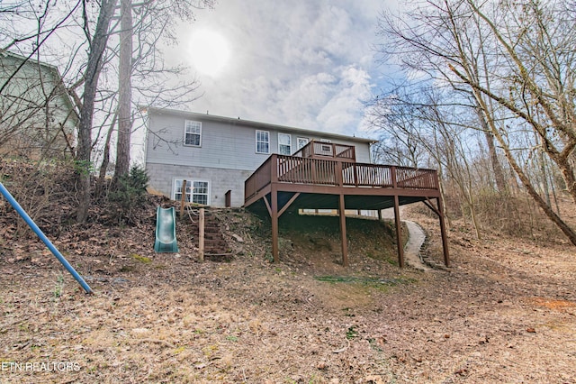 rear view of property featuring a playground and a deck