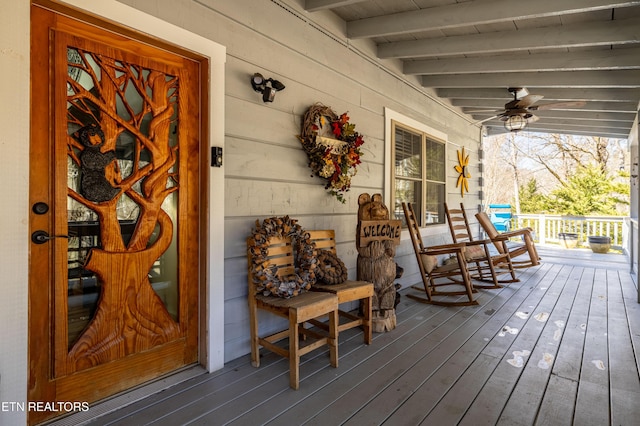 wooden terrace featuring covered porch and a ceiling fan