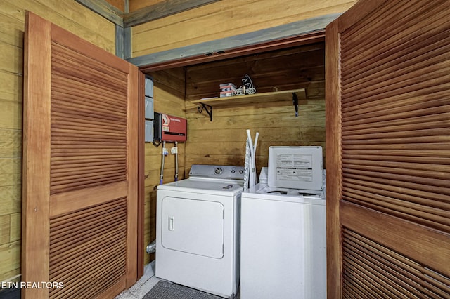 washroom with washing machine and clothes dryer and wooden walls