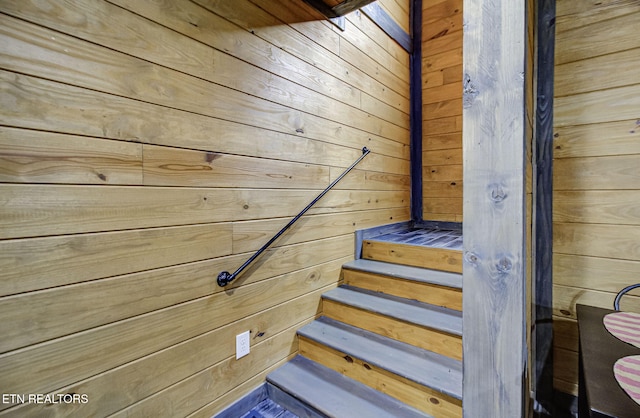 stairway featuring wood walls