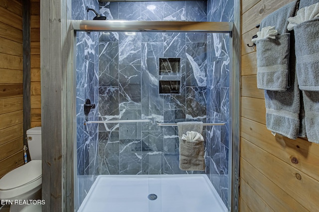 bathroom featuring wooden walls, toilet, and a shower with shower door