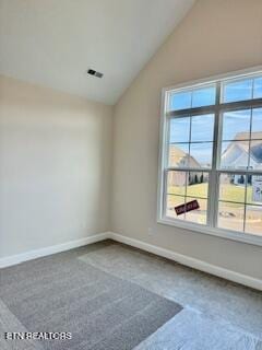 carpeted empty room with plenty of natural light, vaulted ceiling, and baseboards